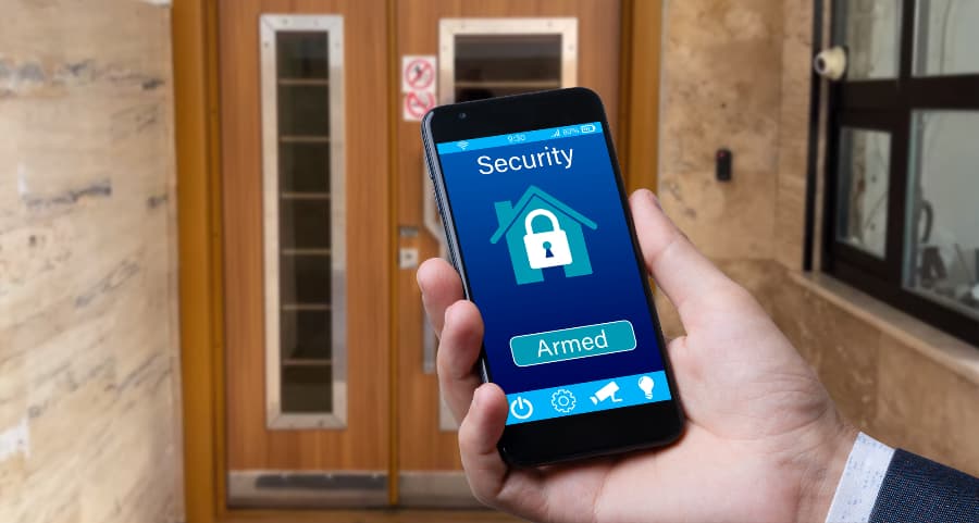 Man using mobile device to arm a home security system